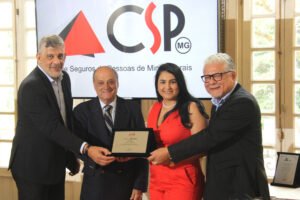 Andreia Cardoso, gerente comercial de Minas Gerais da Solidus Administradora, recebe placa de adesão das mãos dos dirigentes do CSP-MG